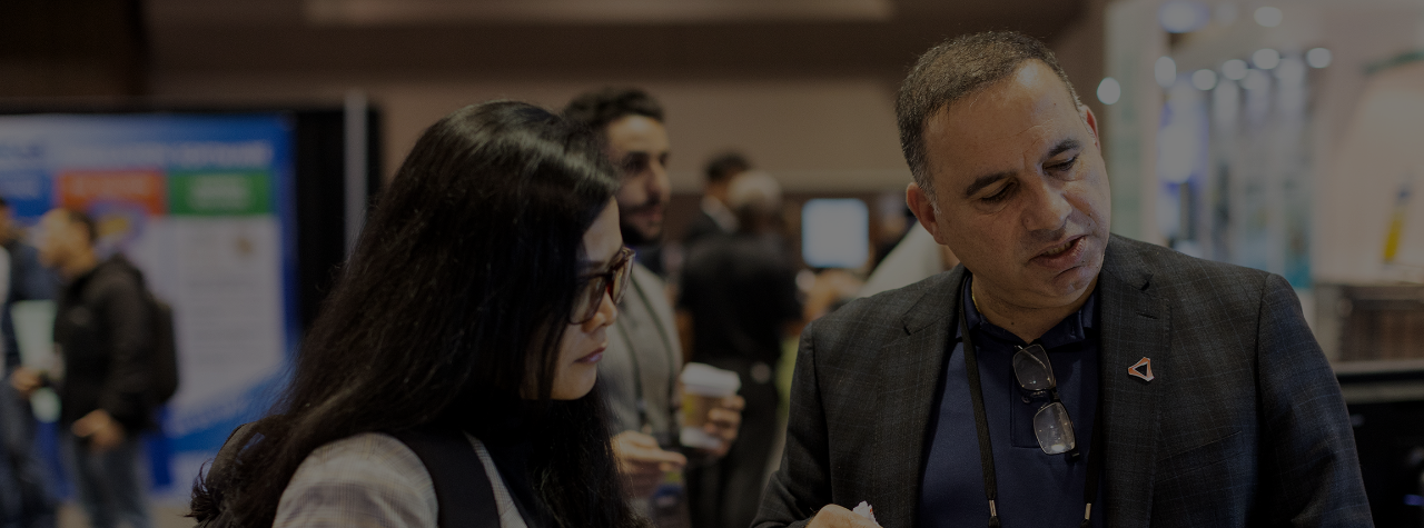 Exhibitor explains a product to an attendee in the DesignCon expo hall.