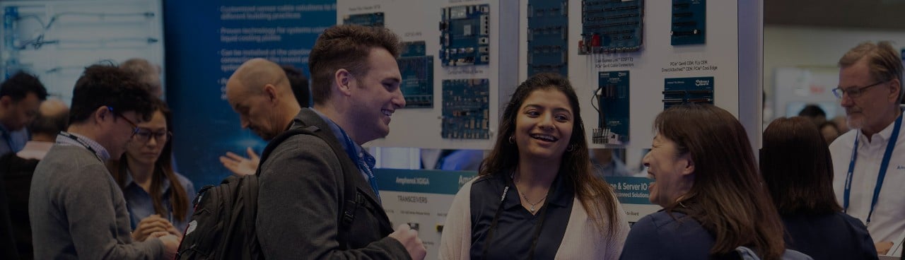 Exhibitor laughs with attendees in the DesignCon expo hall
