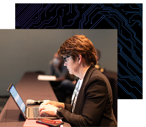 Attendee taking notes on her laptop during a conference session